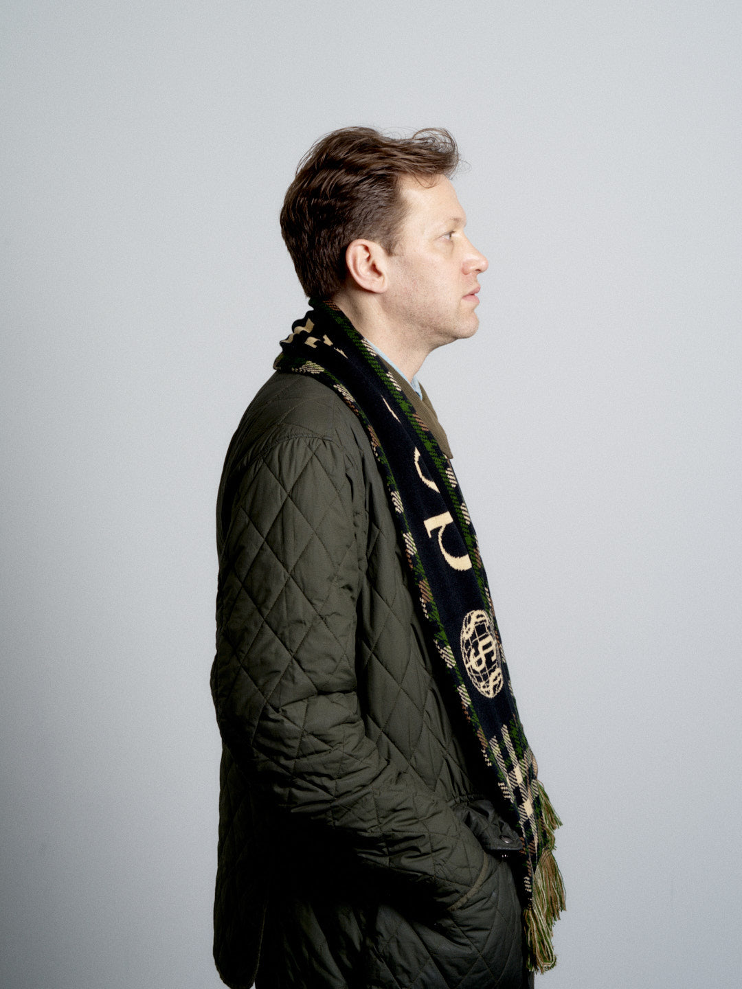 Man wearing a green quilted jacket and deadHYPE Tartan Scarf (Camo) on a gray background