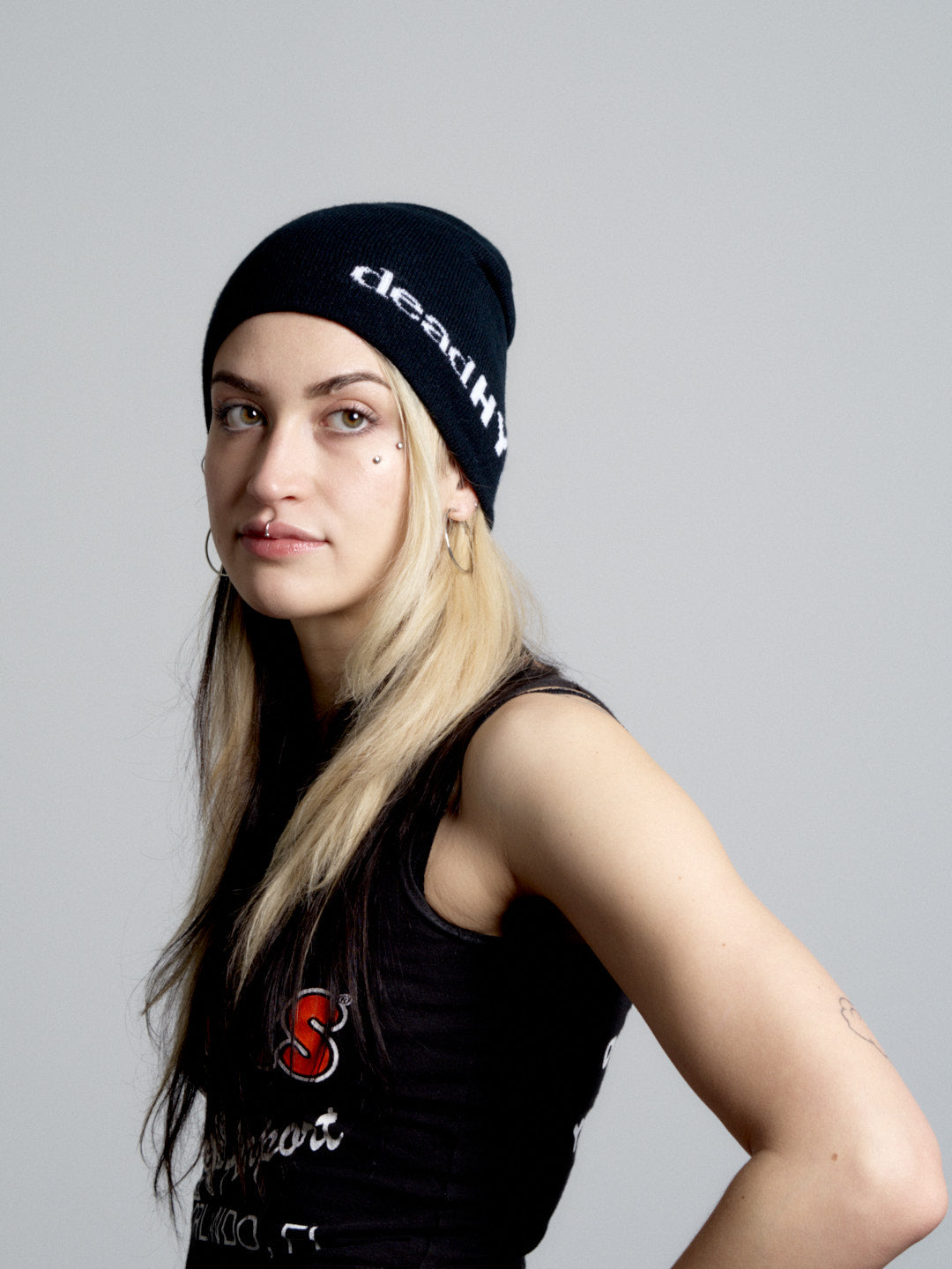 Person wearing a deadHYPE Graphic Beanie (Black) with 'deathly' text and a black tank top with a logo.