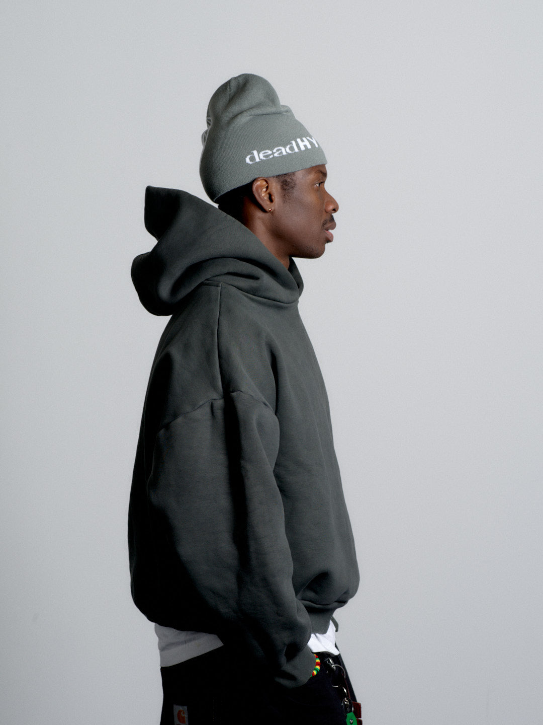 Person wearing a dark hoodie and gray beanie with 'deadhead' text on a light gray background