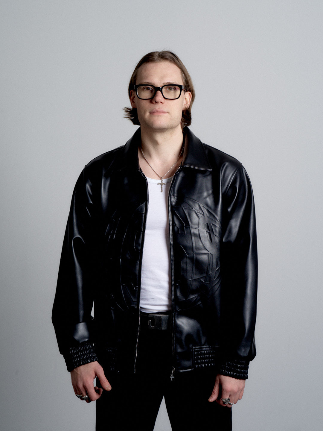 Person wearing a deadHYPE Vegan Leather Jacket (Black) and glasses against a gray background