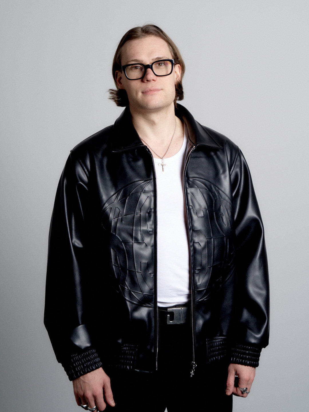 Person wearing a deadHYPE Vegan Leather Jacket (Black) and glasses on a gray background